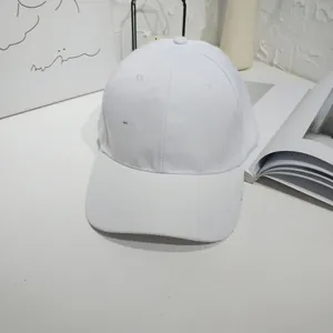 Detail view of a plain white cotton baseball cap in a minimalist setting