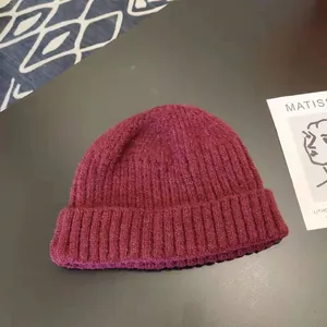 Close-up detail showing the thick ribbed texture of this warm burgundy knitted beanie hat.