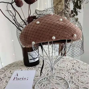 Detail view of brown wool beret with white pearls and black mesh veil decoration