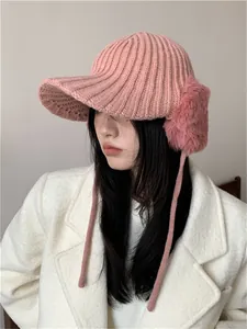 Pink knitted winter hat for women featuring stylish faux fur earmuffs and a brim.