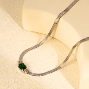 Macro detail of oval emerald zircon set on a silver-toned flat blade chain necklace.