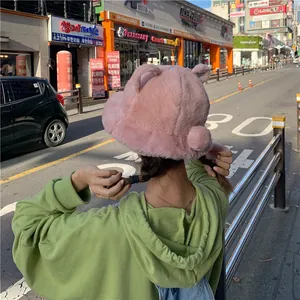 Detail view of a cute pink plush bear ear bucket hat worn in a street setting