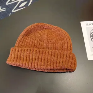 Macro view of brown knitted beanie showing vertical ribbed texture and warm knit material