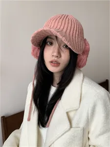 Portrait of a woman wearing a pink knitted winter hat with plush ear protectors.