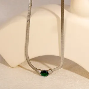 Close-up of vintage silver herringbone necklace with oval green zircon pendant.