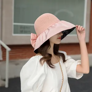 Side view of a woman wearing a pink sun hat with a large bow and black UV lining.