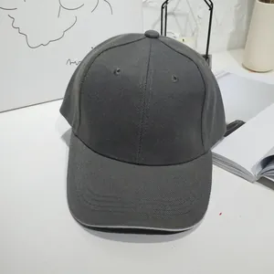 Detail view of a charcoal grey minimalist cotton twill baseball cap on a white desk