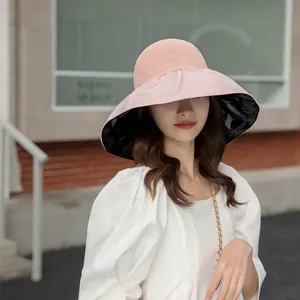 Stylish pink wide brim sun hat with UV protection black coating worn by a model outdoor.