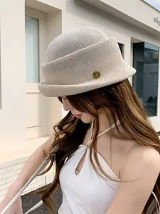 Elegant French Hepburn style beige knitted bucket hat with rolled brim and gold emblem
