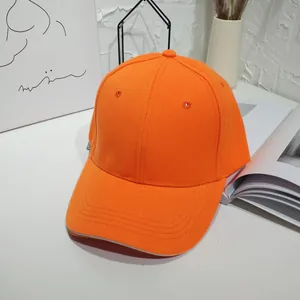 Detailed macro view of a vibrant orange solid baseball cap in a minimalist modern setting.