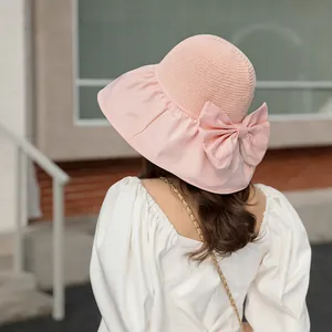 Detail of a pink sun hat with a large bow and hollow mesh top for summer sun protection.
