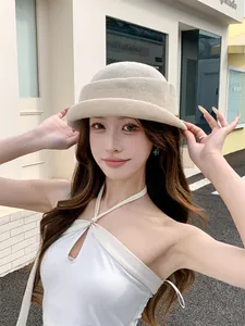 Detailed shot of a model wearing a French style beige knitted bucket hat with rolled edge