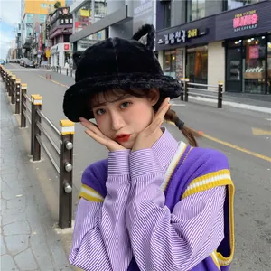 Detailed shot of a black plush cat-ear bucket hat worn by a model in a city street.