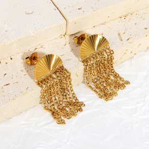 Close-up of gold-plated fan earrings with chain tassels on stone background.