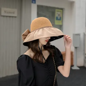 Detail view of a stylish beige sun hat with a bow and black lining for UV protection.
