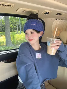 Lifestyle detail of a woman wearing a stylish blue knitted winter headband with a woven label