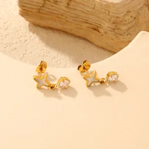 Detailaufnahme von Goldstern-Ohrringen mit weißer Einlage und hängendem Zirkon