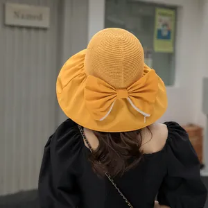 Close-up of yellow sun hat featuring a large bow and knitted texture on the back.