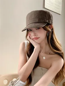 Casquette gavroche marron vintage avec boucle rivetée portée par un mannequin asiatique chic.