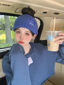 Close-up of a trendy blue knitted headband with logo tag shown on a female model in a car
