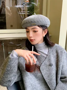 Stylish grey knitted beret hat for women shown in a relaxed outdoor cafe setting.