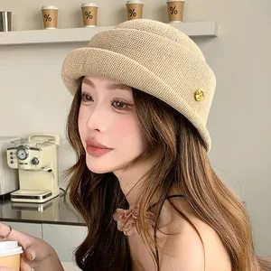 French style beige woven bucket hat with rolled-brim and gold accent for spring.