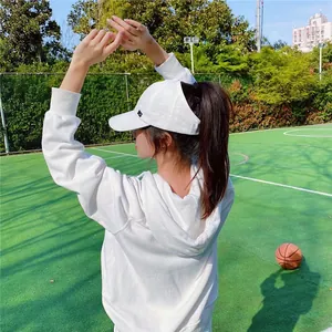 Vue arrière détaillée d'une femme portant une casquette de baseball blanche sur un terrain.
