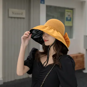 Detailed view of a yellow sun hat featuring UV-resistant black lining and a decorative bow