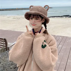 Close-up detail of cute brown plush bucket hat with bear ears worn by model outdoors