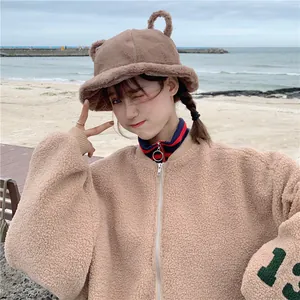 Cute brown plush bucket hat with bear ears for women in a beach winter setting