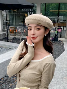 Close-up view of a stylish beige knitted beret for women worn in a cozy outdoor cafe setting