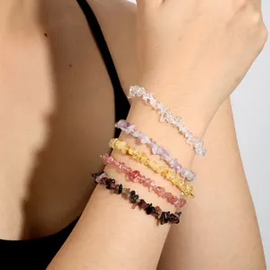 Détail de cinq bracelets en éclats de cristal naturel de différentes couleurs sur un poignet.