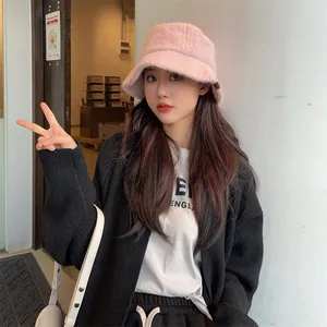 Model wearing a stylish pink fuzzy bucket hat in a cozy indoor setting, autumn winter style