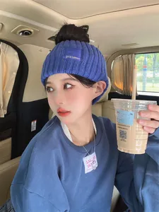 Detailed lifestyle view of an Asian woman wearing a blue knitted wide headband inside a car.