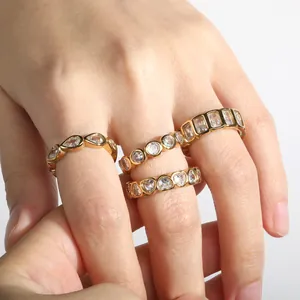 Close-up detail of four stackable gold rings featuring heart and teardrop white zircons.