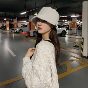 Close-up of a warm white plush bucket hat worn by a model in an urban parking garage