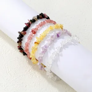 Gros plan de cinq bracelets en éclats de cristaux naturels colorés sur rouleau blanc