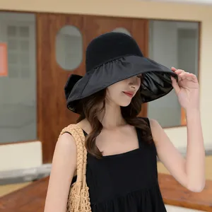 Detail view of women's black wide-brimmed sun hat featuring elegant bow and mesh top