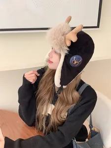 Stylish winter trapper hat with cute reindeer antlers worn by a model in a cozy indoor cafe.