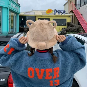 Back view of a cute beige plush bucket hat with bear ears detail, styled with a blue fleece
