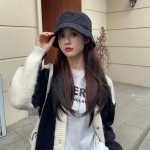 Close-up of a black plush bucket hat worn by a model in a cozy casual setting.