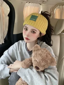 Close-up of an Asian model wearing a yellow knitted headband with a green patch detail
