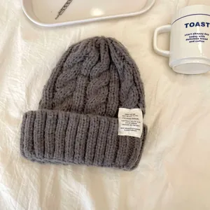Primo piano di un berretto grigio a maglia treccia con etichetta retro in atmosfera accogliente