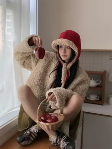 Detail view of red winter trapper hat with soft sherpa lining worn by an Asian model