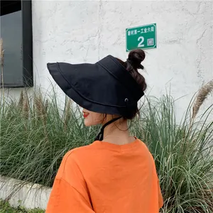 Vue latérale extérieure d'une femme portant un chapeau pare-soleil noir et un t-shirt orange.