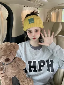 Lifestyle detail of trendy yellow wide knitted headband with letter patch on Asian model