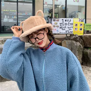 Sweet beige fuzzy bucket hat with cute 3D ears worn by a female model in an outdoor setting
