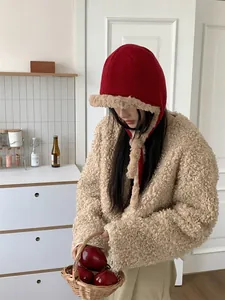 Stylish model wearing a warm red plush ear protection hat in a cozy kitchen setting