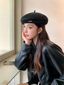 Detail view of a black knitted beret worn by a model in a stylish leather jacket