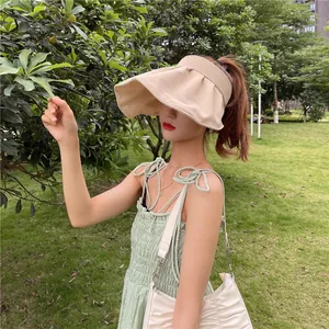 Asiatisches Model mit beigem Sonnenvisier mit breiter Krempe in einem sonnigen Park